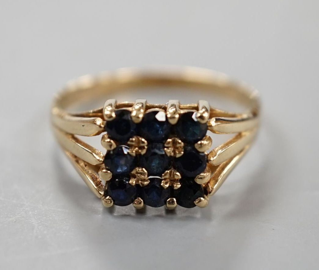 A modern 9ct gold and nine stone sapphire set tablet ring, size R/S, gross weight 2.7 grams.